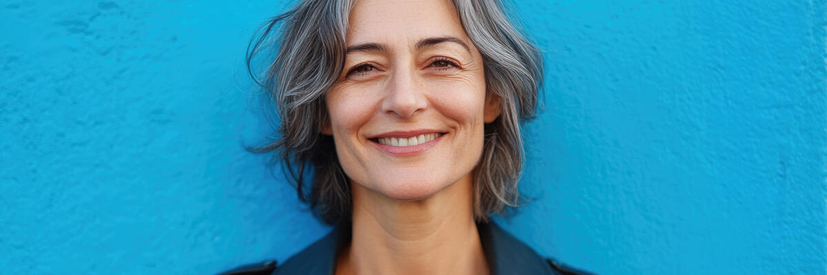Grey haired woman standing in front of blue wall