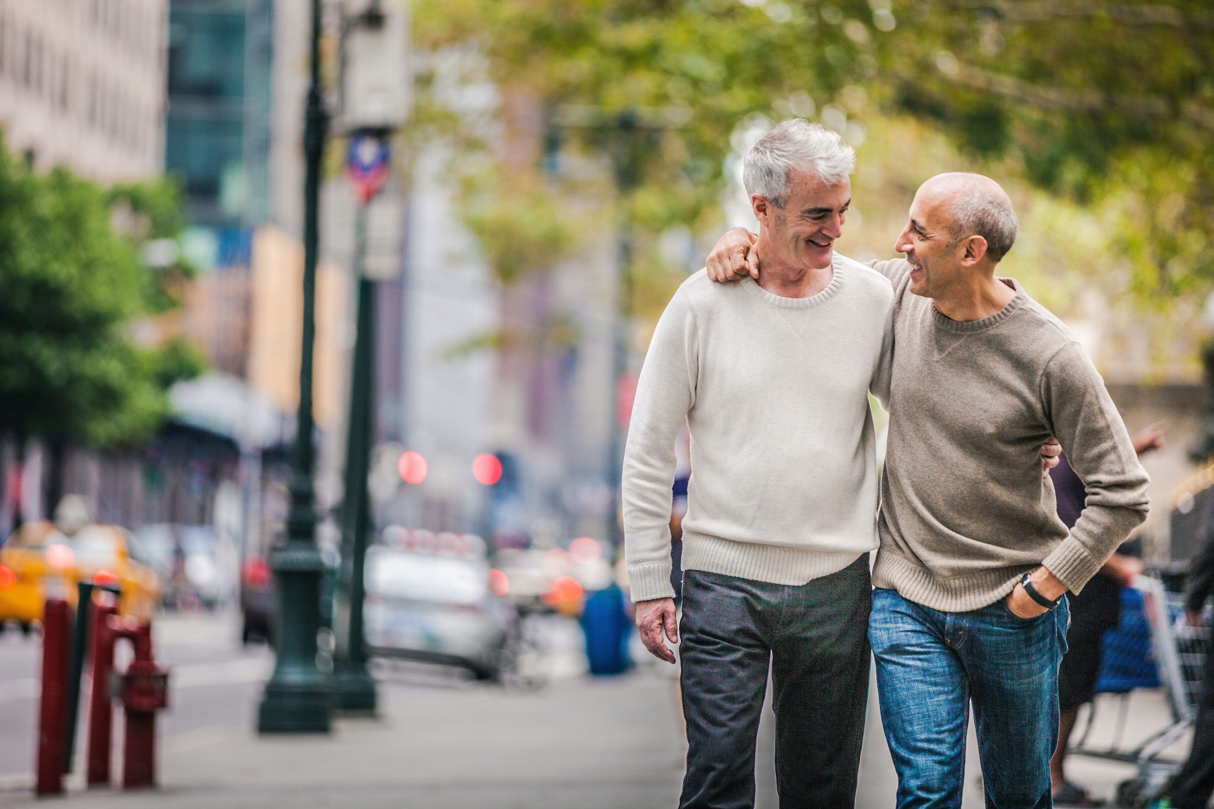 two men walking in a city arms around each other 