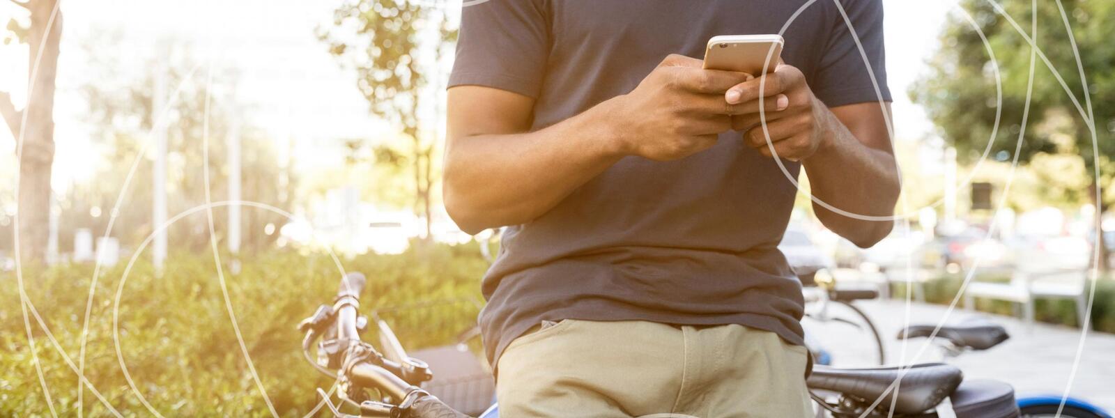 man on his phone leans on a bike