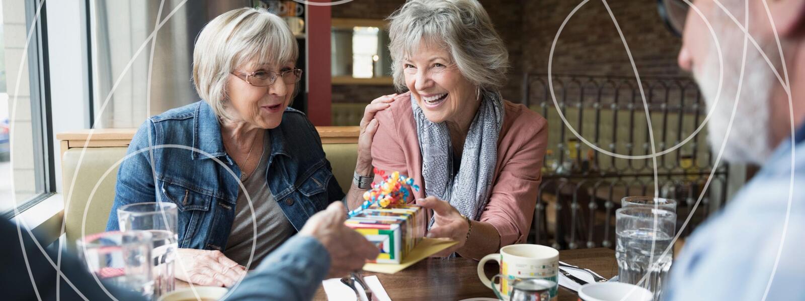 two older women join two older men in coffee and games