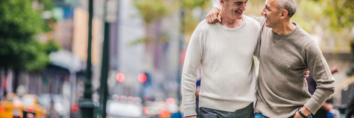 two men walking in a city arms around each other