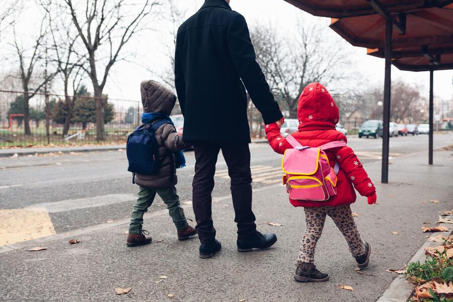 two children walking with their parent 