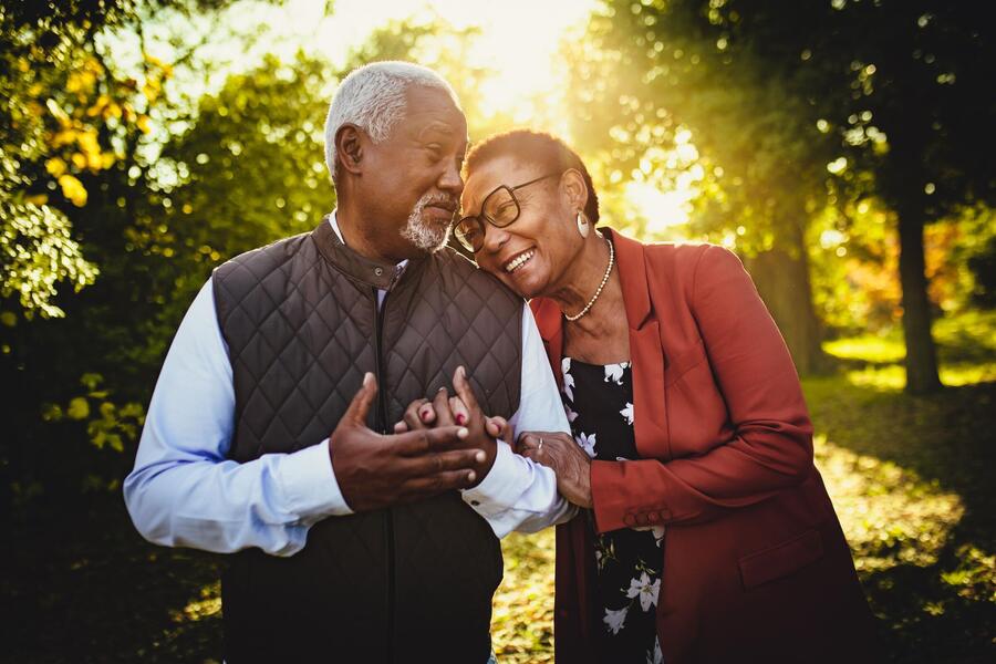 Older adult couple smiles and embraces in the sunshine