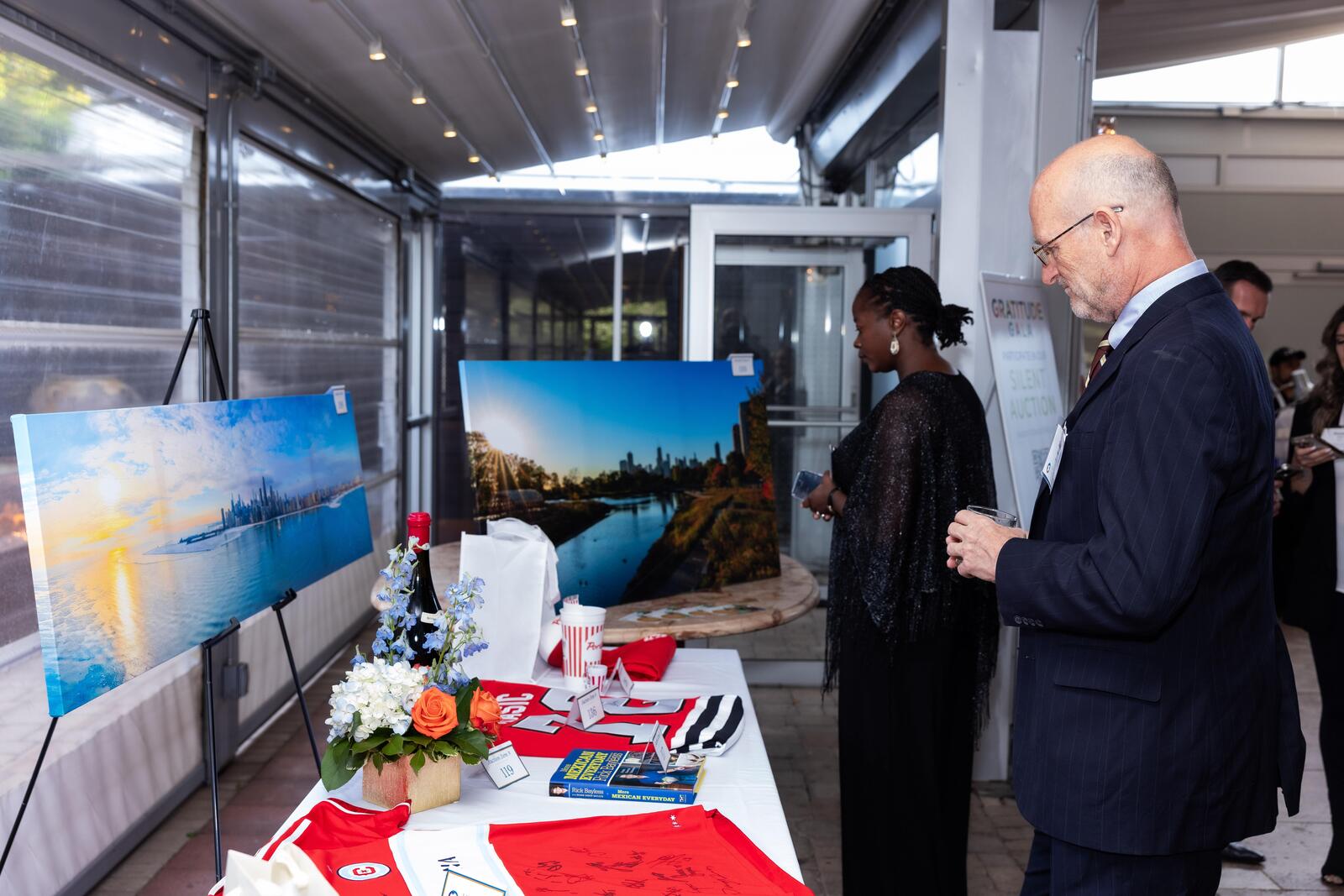 Guests stand at the silent auction table and browse items from signed jerseys to panoramic framed photos of Chicago.