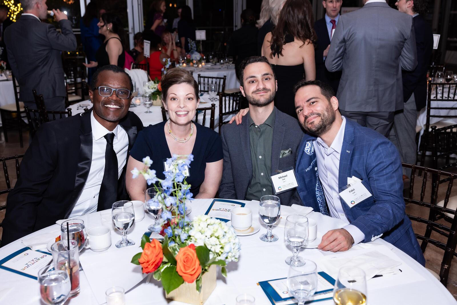 Four guests smile while seated at a table in the dining room at the Gratitude Gala.