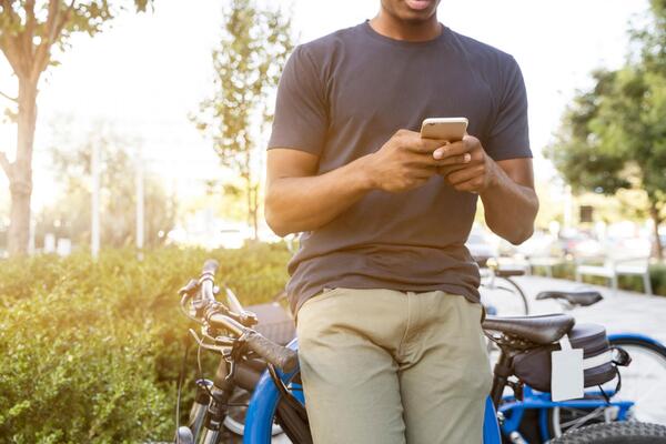 man on his phone leans on a bike