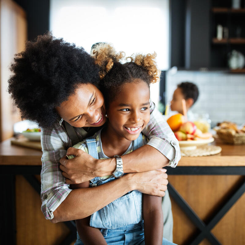 Woman hugging little girl in kitchen